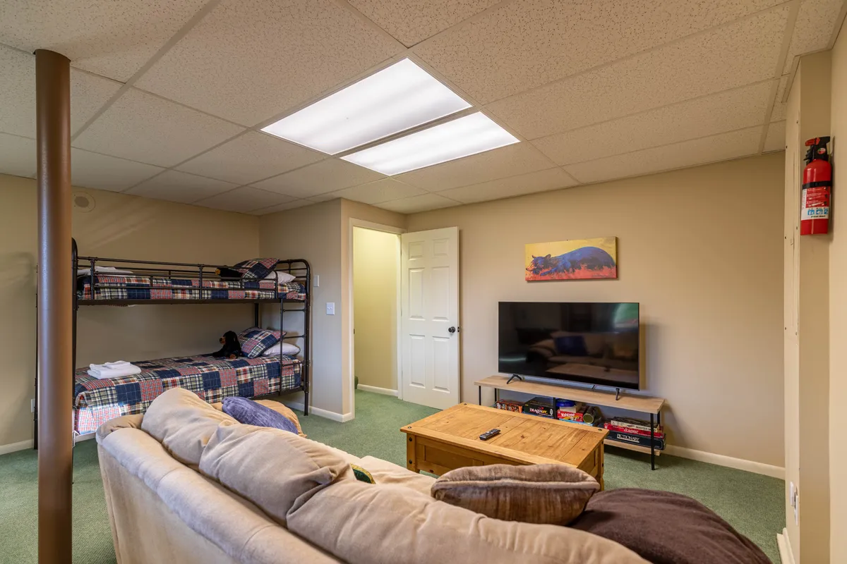 An inviting family-friendly lounge is depicted, featuring twin bunk beds, a sleeper sofa, television, and coffee table. The design is tailored for gatherings, with clear zones for watching TV, playing games, or relaxing. The overall feel is welcoming and versatile.